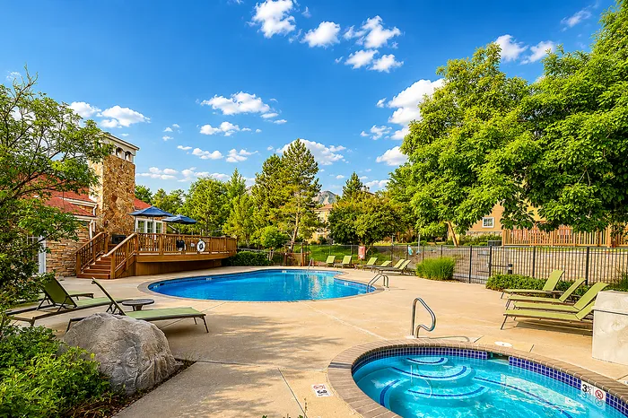 Inviting outdoor pool area with luxurious lounge chairs and a vibrant landscape under a bright blue sky.