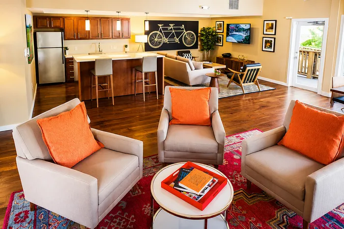 Vibrant open-concept living room with plush seating, chic decor, and a sleek kitchen, bathed in natural light.