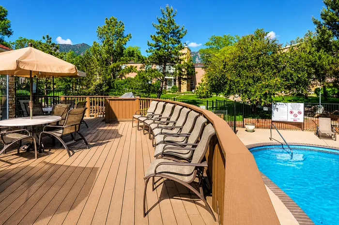 Elegant outdoor pool area with comfortable seating, lush greenery, and mountain views in a serene setting.