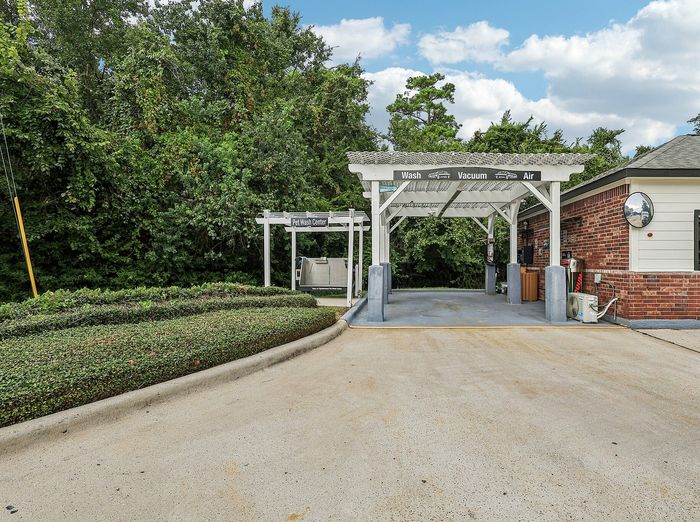 Charming pet wash center with a modern car cleaning bay nestled amidst lush greenery, offering convenience and comfort for pet owners and car enthusiasts.