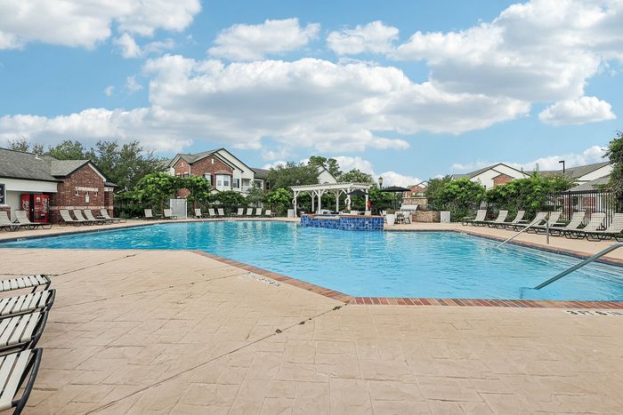Inviting outdoor pool area surrounded by lush greenery and stylish lounge chairs, perfect for relaxation and leisure.