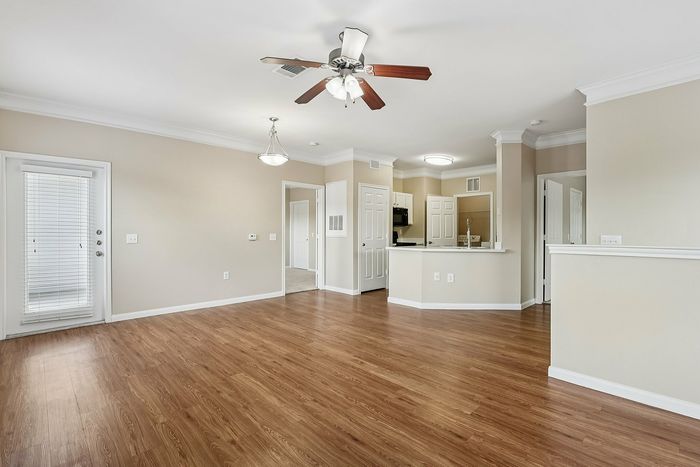Inviting open-plan living area showcasing elegant wood flooring, ceiling fan, and natural light from French doors, ideal for entertaining and relaxation.