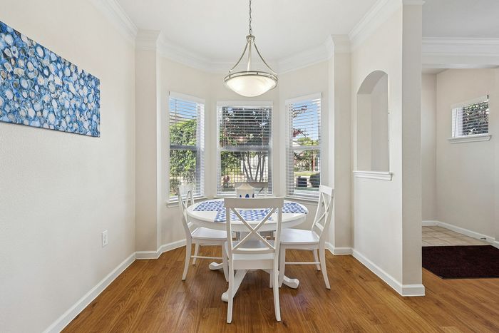 Bright breakfast nook with large windows, elegant chandelier, and charming white dining set with vibrant blue accents, offering a perfect blend of style and comfort.