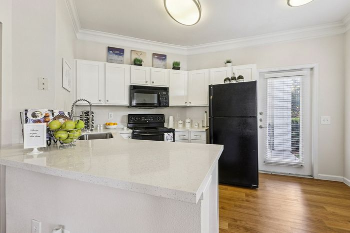 Modern kitchen with elegant white cabinetry, sleek black appliances, and cozy lighting, showcasing a bright and inviting atmosphere.