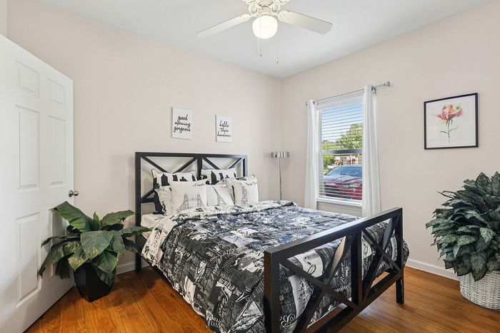 Bright and welcoming bedroom featuring a modern black metal bed, charming decor, and large window with garden views.