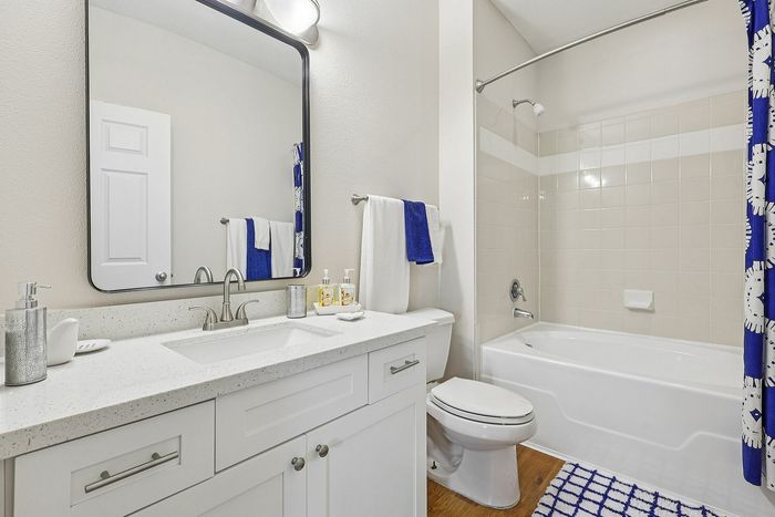 Bright and modern bathroom featuring a sleek white vanity, large mirror, and elegant fixtures, complete with stylish blue accents.