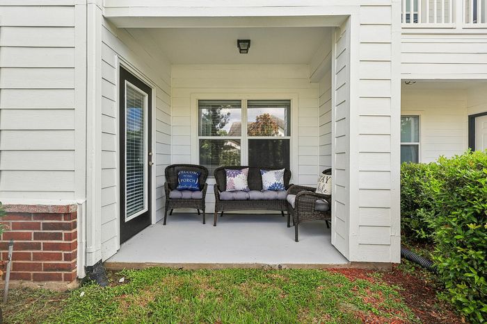 Charming covered porch with cozy seating and decorative pillows, perfect for relaxing in a serene outdoor setting.