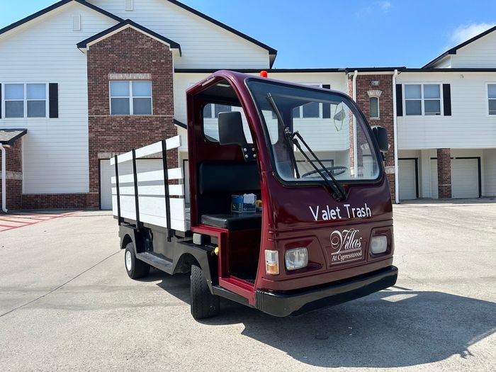 Modern valet trash service truck parked in front of stylish brick apartments, showcasing convenience and contemporary living at Villas at Cypresswood.