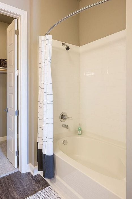 Elegant bathroom with a classic white tub, modern fittings, and a stylish shower curtain, perfect for relaxation and comfort.