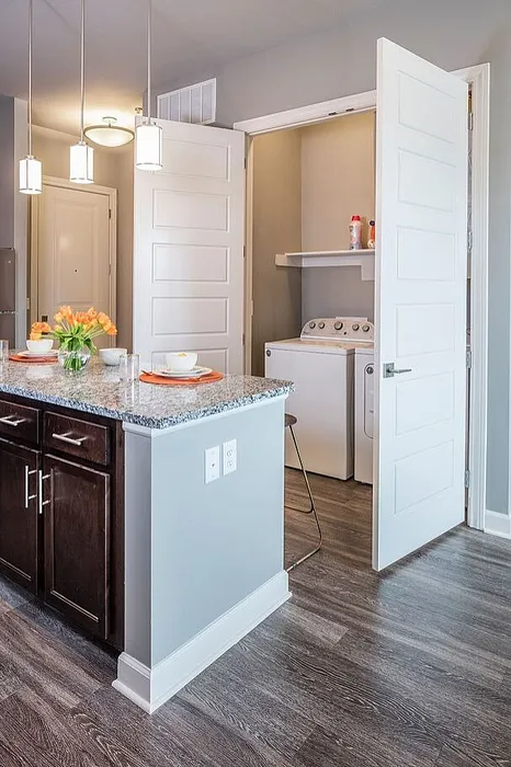 Modern kitchen with elegant granite countertops, pendant lighting, and an adjacent laundry nook for convenience.