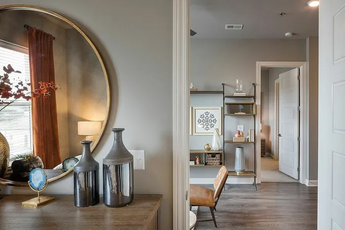 Charming apartment interior showcasing elegant decor with a stylish mirror, artistic vases, and a sleek open shelving unit.