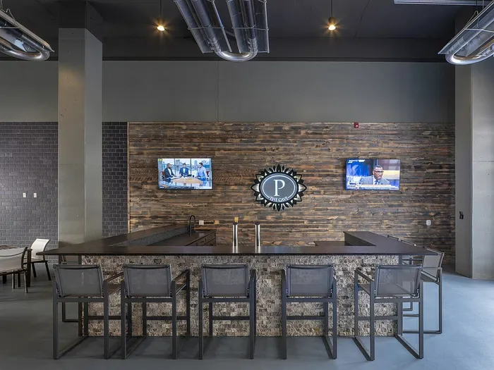 Contemporary lounge area with a stylish bar, comfortable seating, and dual wall-mounted televisions, ideal for socializing and relaxation.