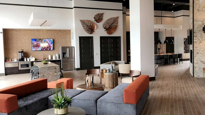 Modern and inviting communal area featuring sleek, contemporary furniture, vibrant decor, and a spacious open layout with stylish wall art and a gourmet kitchen area.