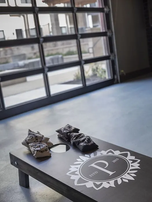 Chic recreational space with a modern glass garage door and custom cornhole game board, perfect for indoor-outdoor entertainment.