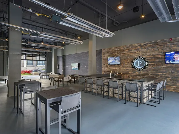 Contemporary indoor lounge with stylish bar seating, modern industrial decor, and ample natural light.