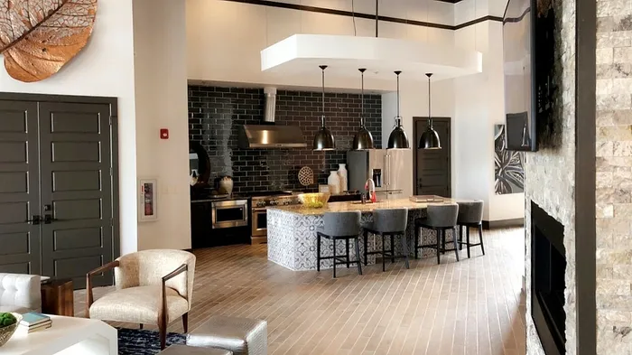 Elegant open-concept kitchen with modern appliances, a chic tile backsplash, and stylish bar seating beneath pendant lighting.