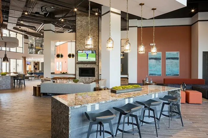 Luxurious apartment lounge with modern decor, featuring a stylish bar area, comfortable seating, and elegant lighting.