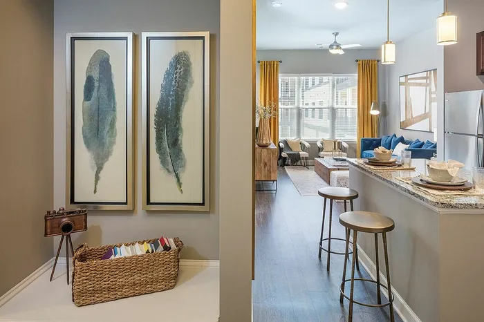Elegant apartment interior showcasing a cozy living area with modern furnishings, vibrant artwork, and a sleek open-concept kitchen with bar seating.