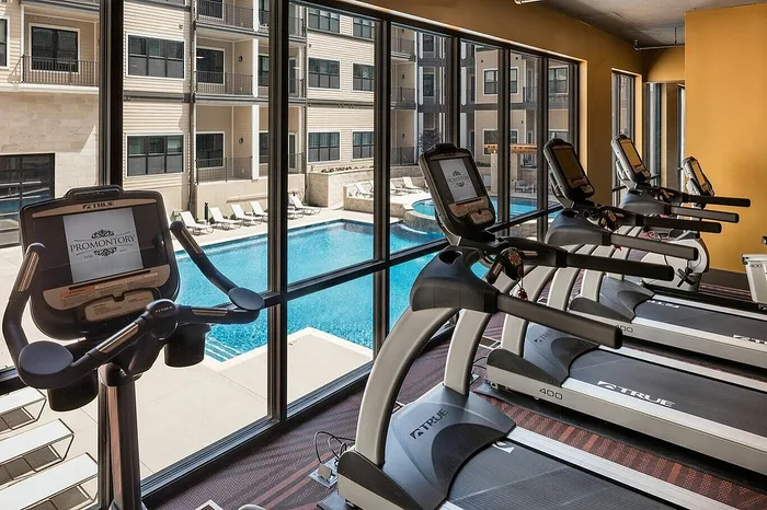 Modern fitness center with treadmills overlooking a luxurious outdoor pool area, perfect for an invigorating workout with a view.