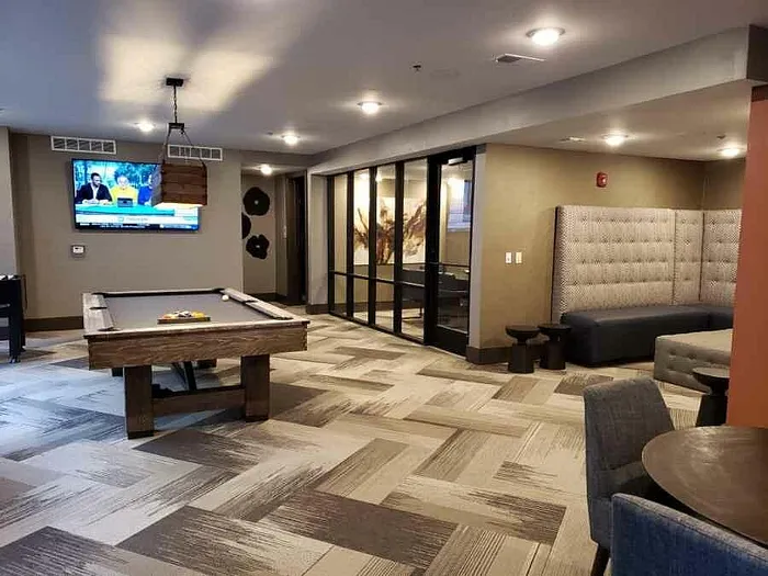 Chic and modern recreation room featuring a pool table, cozy booth seating, and a mounted TV, perfect for entertainment and relaxation.