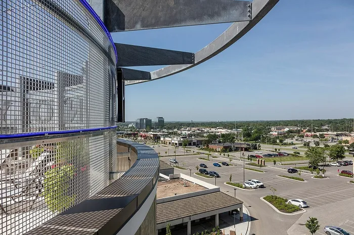 Breathtaking urban view from a modern balcony showcasing cityscape and open parking space beneath clear skies.