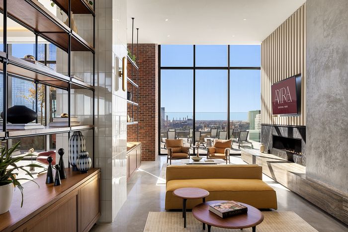 Luxurious modern living room with floor-to-ceiling windows offering stunning city views, stylish shelving, and elegant decor.