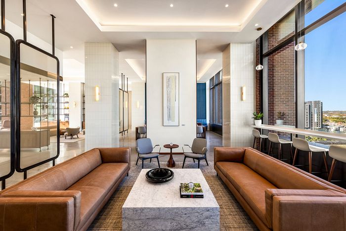 Luxurious modern living area with sleek leather sofas, elegant marble coffee table, and floor-to-ceiling windows offering stunning city views. Perfect blend of style and comfort.
