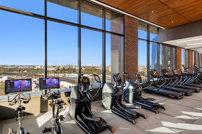 Modern gym with panoramic city views, featuring state-of-the-art exercise bikes and elliptical machines for a premium workout experience.