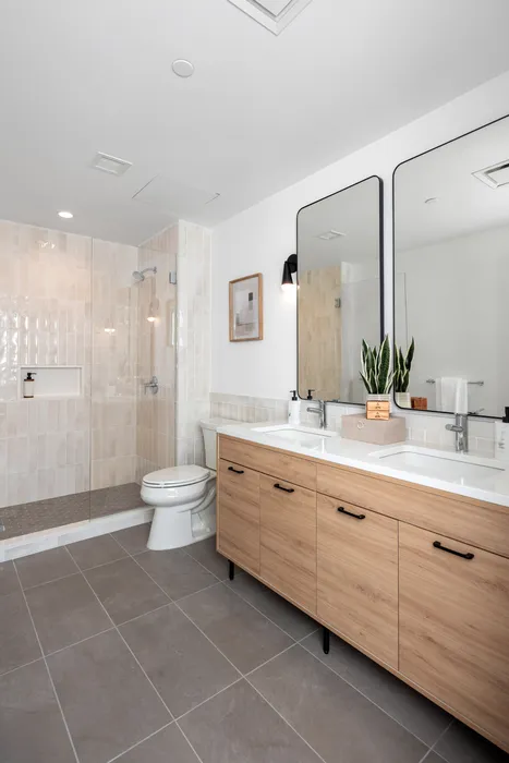 Elegant bathroom with a modern double vanity, sleek glass shower, and stylish tiles.