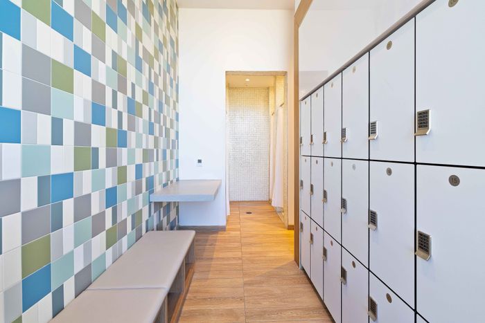 Modern apartment entryway featuring sleek lockers, colorful tiled accent wall, and chic wooden flooring for a stylish welcome.