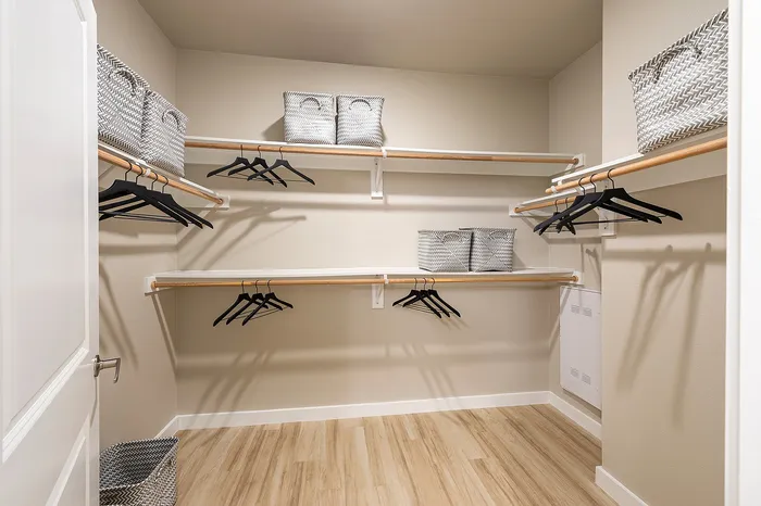Spacious walk-in closet with elegant shelving, modern hangers, and stylish storage baskets, perfect for organized living.
