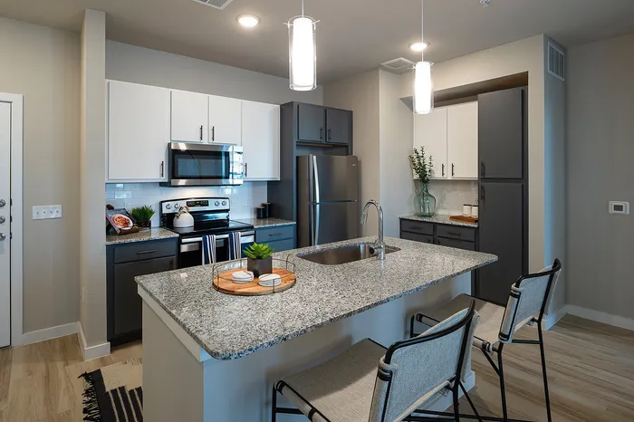 Modern kitchen with granite countertops, stainless steel appliances, stylish pendant lighting, and chic bar seating.