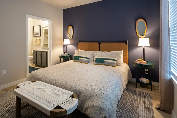 Elegant bedroom with chic decor, accented by dual mirrors, cozy bedding, and ambient lighting creating a warm, inviting atmosphere.