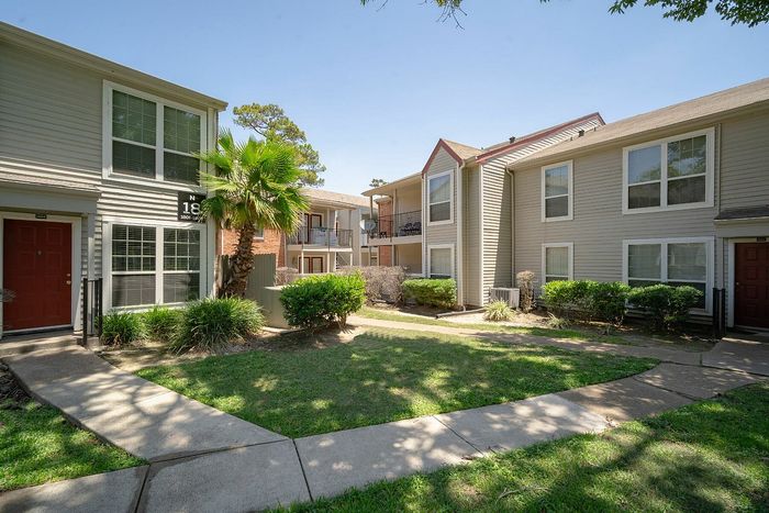 Charming apartment complex with lush green landscaping, inviting walkways, and modern exterior design.