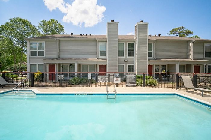 Inviting apartment complex with charming red doors and a sparkling swimming pool, offering a refreshing oasis for residents.
