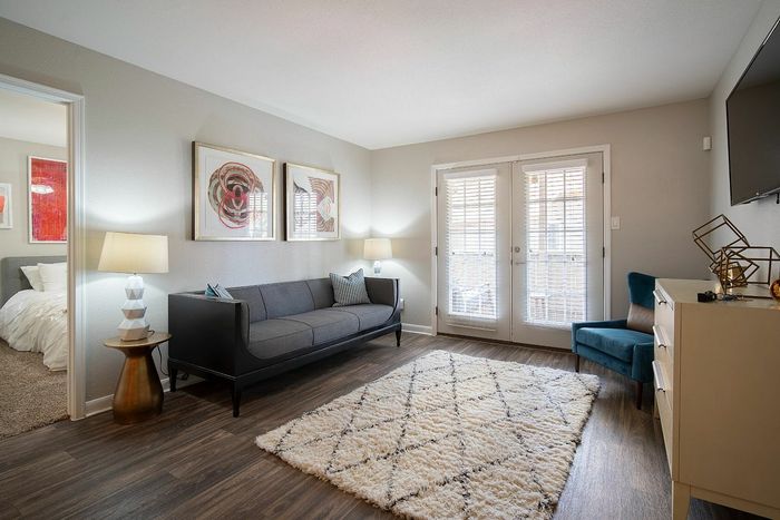 Inviting living room with elegant decor, cozy gray sofa, soft area rug, and sunlit French doors leading to a serene view.