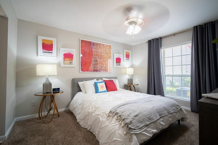 Elegant bedroom featuring a plush bed, stylish decor, and ample natural light through large windows.