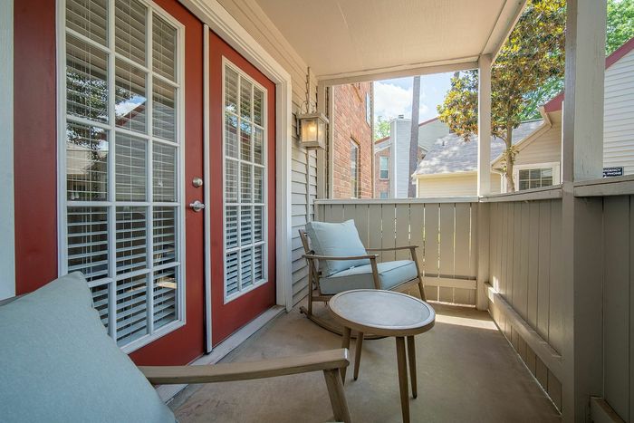 Charming apartment balcony with red-framed glass doors and cozy seating for relaxing.