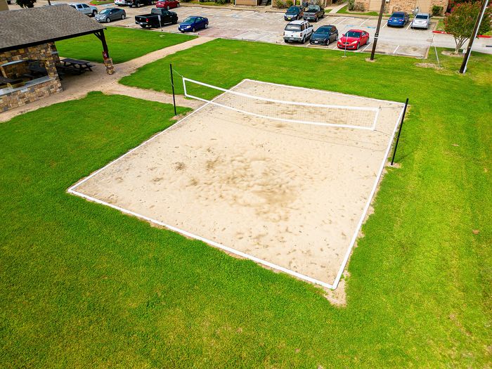 Inviting outdoor sand volleyball court surrounded by lush green grass, perfect for recreational activities and relaxation.