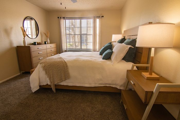 Inviting bedroom with natural light, cozy bed, modern wooden furniture, and stylish decor accents.