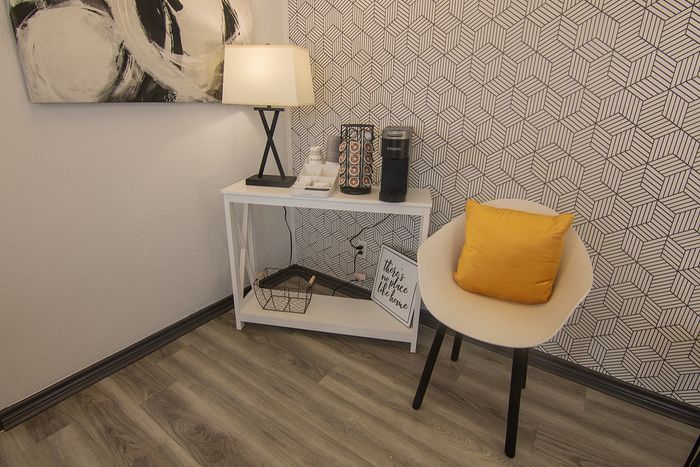 Chic cozy corner with modern art, geometric wallpaper, and coffee station for a stylish touch.