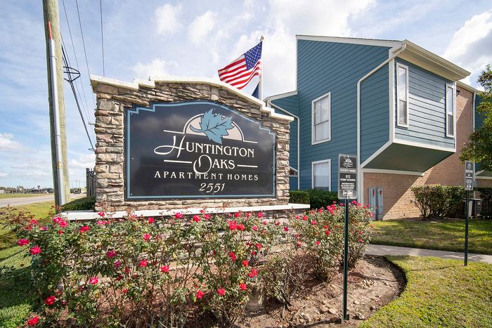 Charming entrance to Huntington Oaks Apartment Homes with vibrant landscaping and a welcoming community sign.