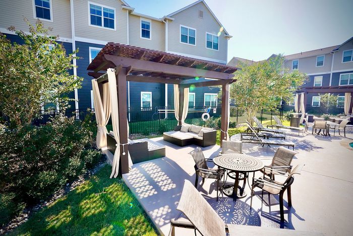 Charming outdoor patio featuring a shaded pergola, cozy seating area, and stylish dining set, perfect for relaxation and entertaining.