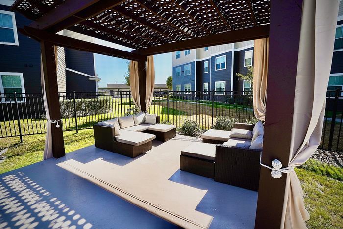 Inviting outdoor seating area under a stylish pergola, featuring cozy cushions and elegant curtains, perfect for relaxation and social gatherings.