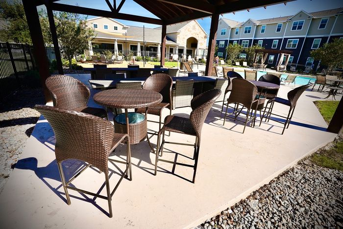 Charming outdoor seating area with stylish wicker chairs and tables overlooking a sparkling pool, perfect for relaxation and entertaining.