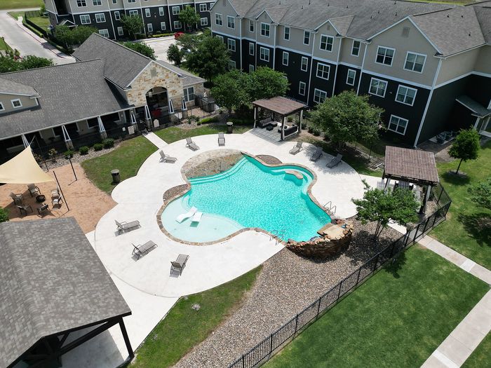 Elegant apartment complex featuring a beautifully designed swimming pool, spacious lounge areas, and lush landscaping.