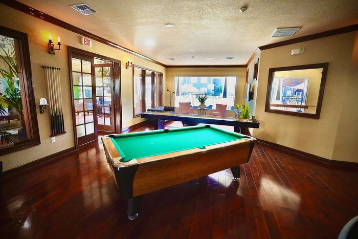 Luxurious recreation room with a sleek billiards table and vibrant natural light, perfect for entertainment and relaxation.