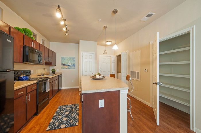 Modern kitchen with rich wooden cabinets, sleek countertops, and an inviting island, complemented by stylish lighting and spacious shelving.