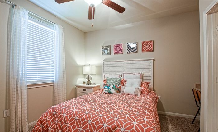 Cozy bedroom with modern decor, featuring a vibrant orange-patterned bedspread, elegant side table, and stylish wall art.