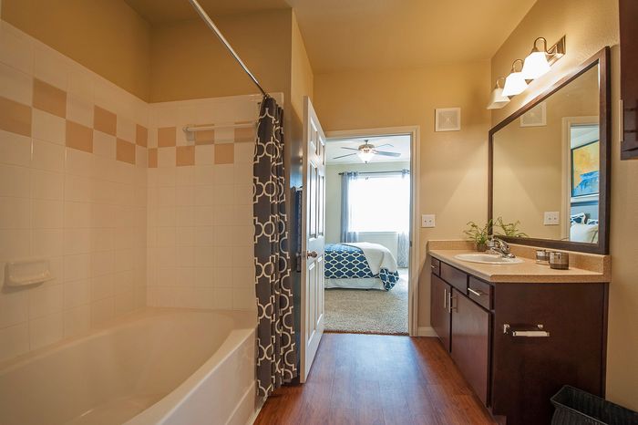 Inviting bathroom with elegant tile work and modern fixtures leading to a cozy bedroom with natural light accentuating the plush carpet and stylish decor.